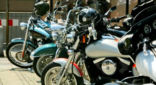 Kilka motocykli zaparkowanych na chodniku, w tym niebieski, zielony i srebrny.