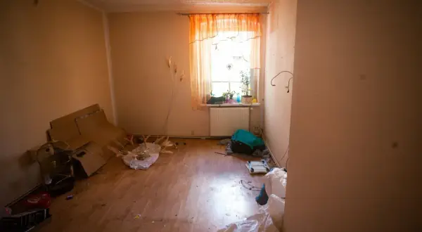 Zalane mieszkanie, stosy kartonów, klatka dla ptaków i worki. Spółdzielnia ponosi odpowiedzialność za zalanie mieszkania, co widać po zniszczeniach.