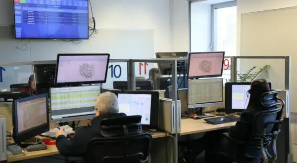 Operatorzy 112 pracują w centrum dowodzenia, monitorując sytuację na mapach i danych.