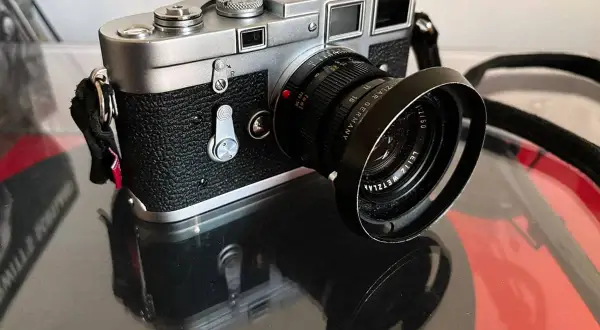 A classic Leica M3 camera with a Leitz Wetzlar lens sits on a reflective surface, ready to capture timeless moments.