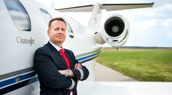 Pilot w mundurze z odznaką na rękawie opiera się o CitationJet. Marzysz, jak zostać pilotem?