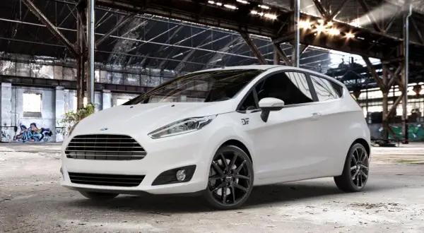 Weißer Ford Fiesta mit schwarzen Felgen in einer Industriehalle.