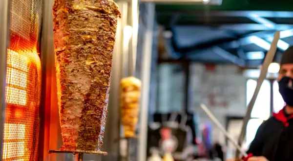 Obracający się, pionowy szpikulec z soczystym, kraftowym mięsem kebab, pieczonym przy rozgrzanej lampie.