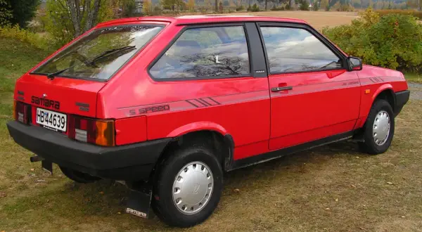 En röd Lada Samara står parkerad på en gräsmatta. Bilen har en "5 SPEED"-dekal på sidan.