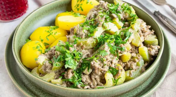 Schmorgurken mit Hack, Omas Rezept: Ein deftiger Eintopf mit Hackfleisch, Gurkenstücken und Salzkartoffeln, garniert mit Petersilie.