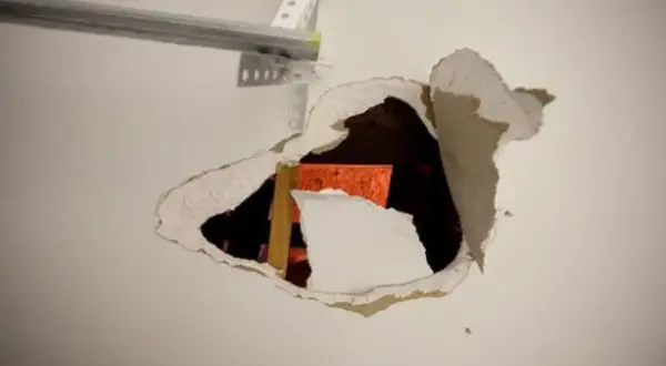 Un **buco nel muro troppo grande** rivela una struttura arancione e un montante di legno.
