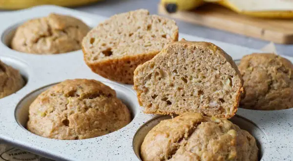 Saftige bananenmuffins ohne zucker, gebacken in einer Muffinform. Eine Hälfte ist aufgeschnitten und zeigt die lockere Krume.