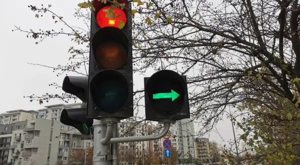 Sygnalizacja świetlna z czerwonym światłem na górze i zieloną strzałką w prawo.