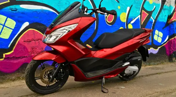 Czerwony skuter Honda PCX 125 na tle kolorowego graffiti. Wyobraź sobie, że to Twój nowy pojazd, gotowy na jazdę z prędkością v-max!