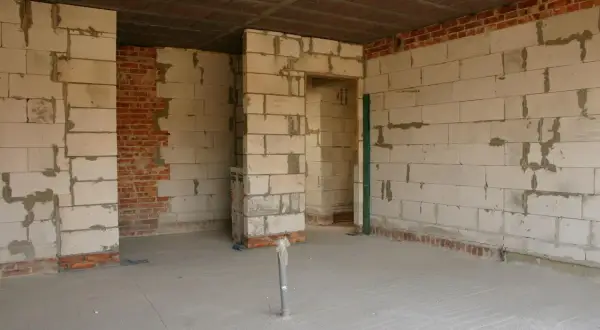 Budowa wnętrza z bloczków betonowych, widoczna ścianka działowa z gk w trakcie prac.