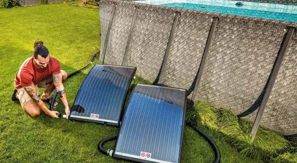 Mann schließt Solarmatten an, um den Pool zu heizen.