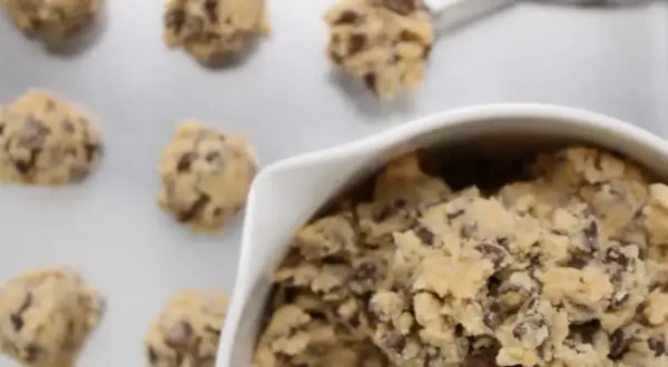 Frisch geformte american cookies mit Schokostückchen auf einem Backblech, bereit zum Backen.