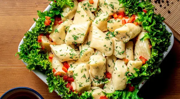 Pyszne pierogi ze szpinakiem, posypane koperkiem i papryką, otoczone sałatą. Idealne na obiad!