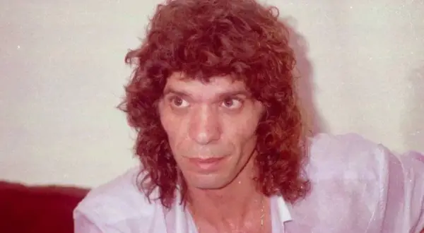 Primer plano de un hombre con cabello rizado y camisa rosa. Se especula a qué edad murió Camarón.