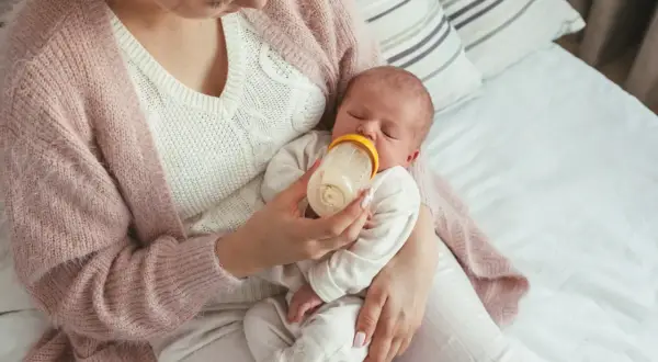 Mama karmi noworodka butelką, ucząc się jak karmić noworodka butelką.