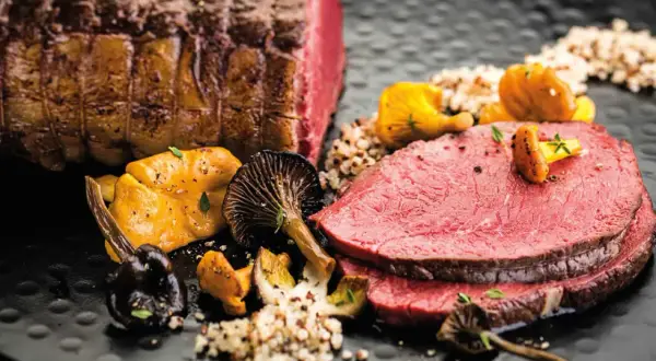Zarter Rinderbraten im Ofen, perfekt geschnitten, serviert mit Pilzen und Quinoa. Ein Festmahl!