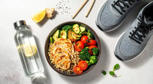 Un repas équilibré pour savoir que manger avant le sport : poulet grillé, quinoa, légumes et eau citronnée. Prêt pour l'effort !