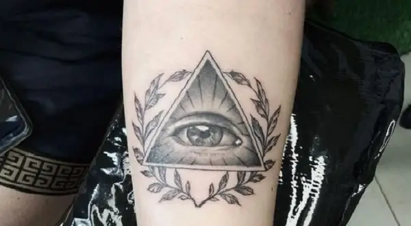 Oko proroka tatuaz w trójkącie otoczone gałązkami. Symbol czujności i wiedzy.