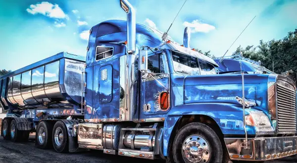 Un camion us bleu étincelant, prêt pour la route. Le chrome brille sous le ciel bleu.