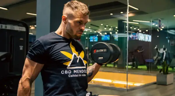 Mężczyzna ćwiczy z hantlem 15kg. Zastanawiasz się, ile trwa trening na siłowni? Kluczowe jest efektywne wykorzystanie czasu.