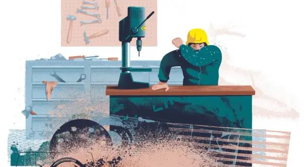 En person i verkstaden hostar i armvecket, en påminnelse om vad som kan hända om man skadar sig på jobbet.