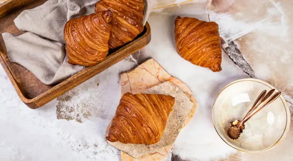 Złociste, chrupiące rogaliki na marmurowym blacie. Idealny croissant przepis na pyszne śniadanie.