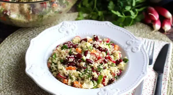En härlig couscous sallad med bönor, rädisor och örter serveras på en vit tallrik.