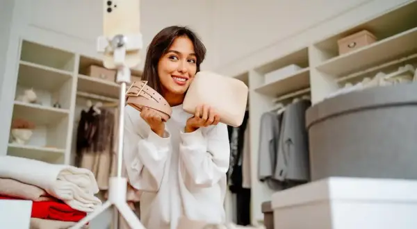 Uśmiechnięta influencerka prezentuje pasek i kosmetyczkę, wyznaczając nowe trendy.