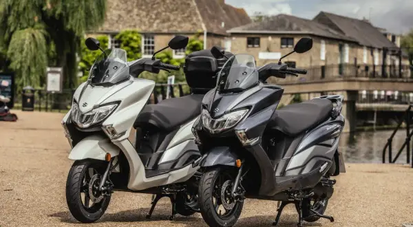 Dwa skutery Suzuki Burgman, biały i grafitowy, stoją obok siebie. To największe skutery 125, gotowe na miejskie przygody.