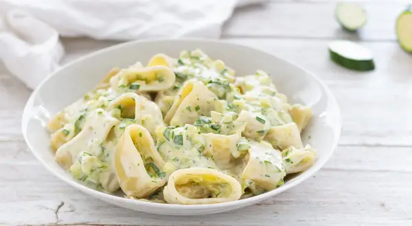 Piatto di pasta robiola e zucchine, cremoso e invitante, con pezzi di zucchine fresche e erbe aromatiche.