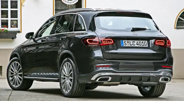 Ciemnoszary Mercedes-Benz GLC 300e z eleganckimi światłami LED i chromowanymi końcówkami wydechu, zaparkowany przed budynkiem z oknem.