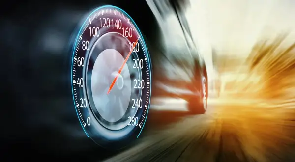 Prędkościomierz pokazuje ponad 180 km/h. Samochód pędzi drogą ekspresową, rozmazując krajobraz.