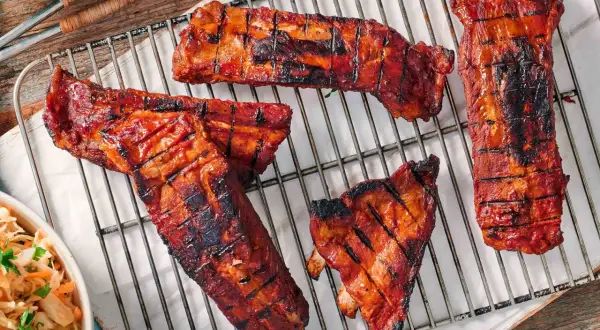 Saftige Rippchen mit glasiertem, karamellisiertem Fleisch auf einem Grillrost. Perfekt für eine rippchen marinade einfach.