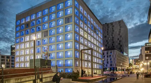 Die Stadtbibliothek Stuttgart leuchtet in der Dämmerung mit blauen Fenstern.