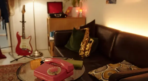 Un salotto in stile dark academia con chitarra rossa, sassofono, telefono vintage e giradischi.