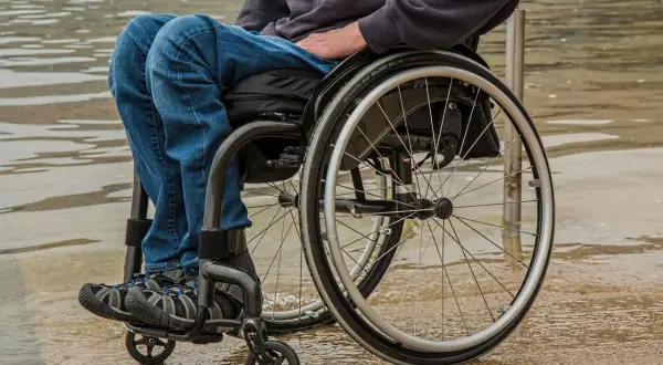 Osoba na wózku inwalidzkim, zmagająca się z rozszczepem kręgosłupa. Czy da się wyleczyć? Nadzieja i determinacja w codziennym życiu.