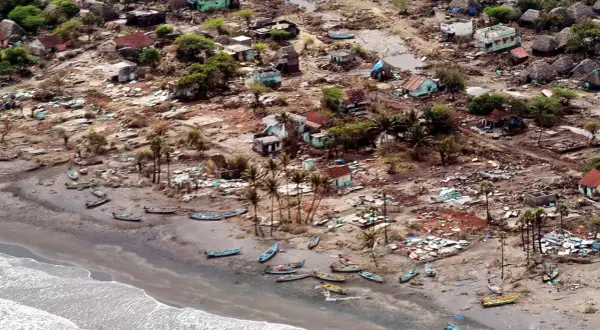 En by ödelagd av tsunamin 2004. Hus är raserade, båtar ligger utspridda på stranden. Bilden ger en känsla av förödelsen och väcker frågan: hur många dog i tsunamin 2004?