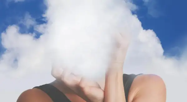 Osoba z twarzą ukrytą w chmurach, symbolizująca mgłę mózgową.
