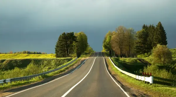 Droga pnie się ku niebu, otoczona zielenią i żółtym polem. Zrid, podróż trwa.