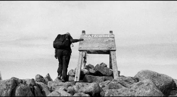 A lone hiker reaches the summit of Katahdin, a testament to perseverance in this striking fine art photography.