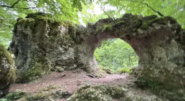 Arco natural cubierto de musgo en la sierra de Entzia, ideal para rutas de senderismo.