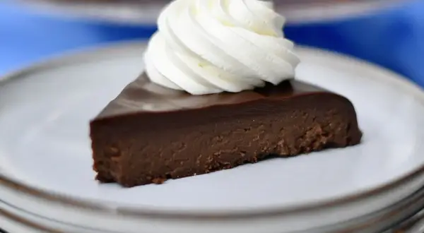 En bit fransk chokladtårta med en virvel av vispad grädde på en tallrik.