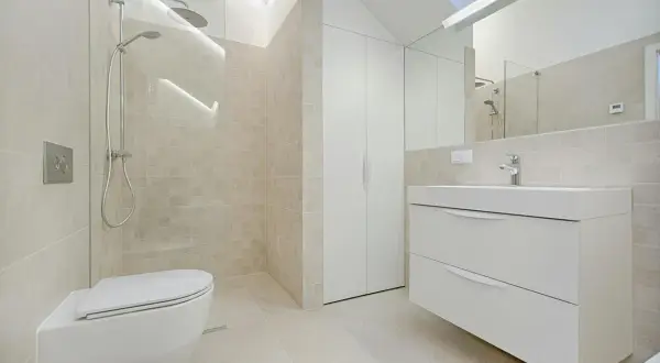 Baño moderno con ducha, inodoro y mueble de lavabo flotante. La decoración de baños pequeños se inspira en la luz y los tonos neutros.