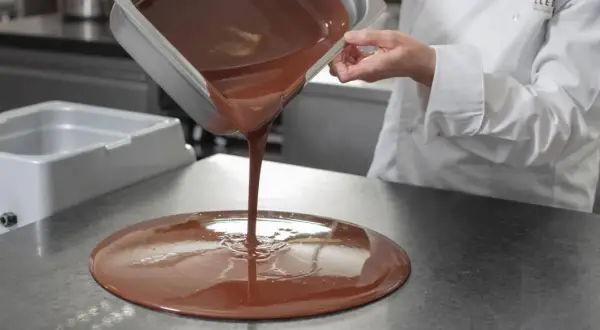 Un chef verse du chocolat fondu. Mycryo, c'est quoi ? C'est la magie du chocolat qui prend forme.
