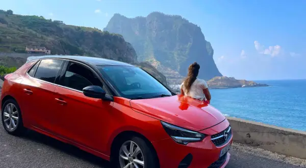 Roter Opel auf Madeira, bereit für eine Fahrt entlang der Küste mit Blick auf die dramatischen Berge und das blaue Meer.