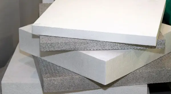 Pannelli bianchi e grigi di piastrelle isolanti termiche impilati, pronti per l'isolamento edilizio.