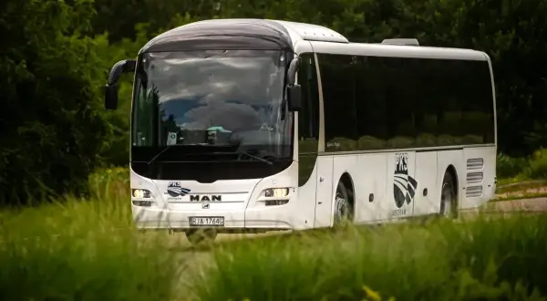 Biały autokar PKS Jarosław jedzie przez zielony krajobraz, być może w drodze do Horyńca-Zdroju.