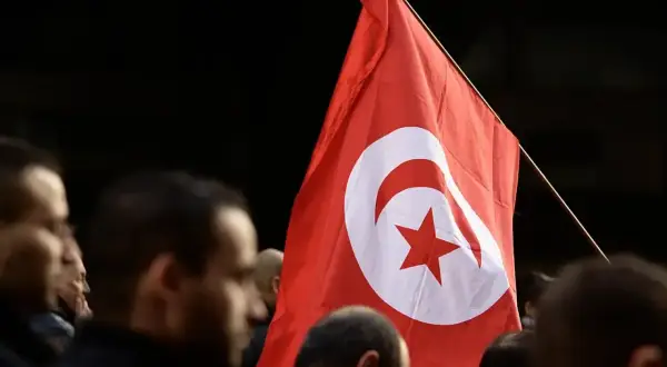 Flaga Tunezji powiewa wśród tłumu. Czy Tunezja jest bezpieczna? Ludzie z flagą, symbol nadziei i jedności.