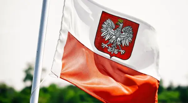 Flaga Polski z orłem, symbol wolności i niezależności. W tle zieleń, jak w kraju, gdzie zagraniczne banki w Polsce rozwijają skrzydła.