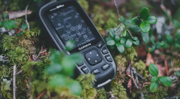 Garmin inReach, jako akcesoria do komunikacji satelitarnej, leży na mchu w lesie.